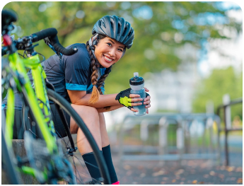 Female bicycler taking a break and holding a water bottle.